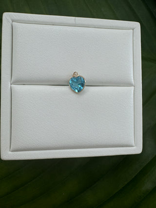 Blue topaz heart pendant in a 14k gold setting on a white jewelry display.