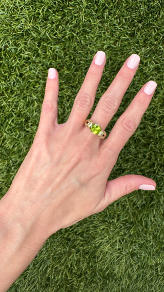 Gold peridot ring worn on a hand to show its size.