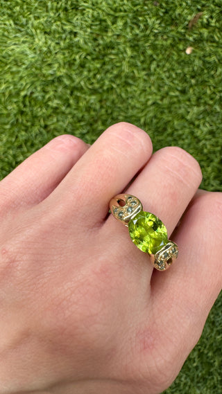Close-up of a gold peridot ring worn on a hand.