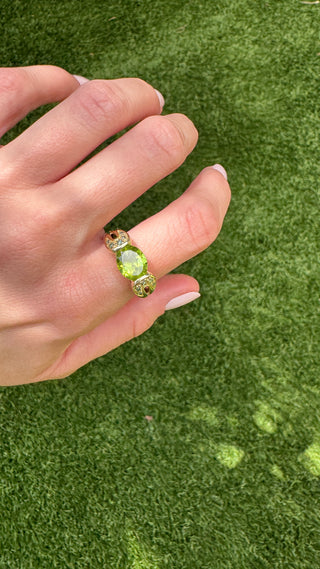 Close-up of a gold peridot ring worn on a hand.