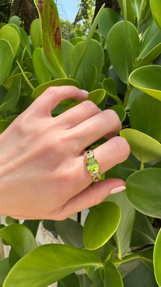 Gold peridot ring worn on a hand.