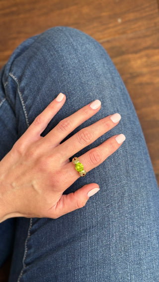 Gold peridot ring worn on a hand.