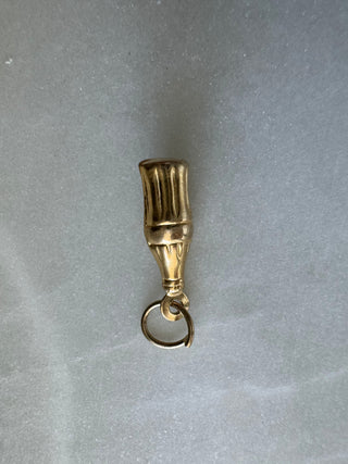 Rear view of a vintage gold cola bottle charm showing its rounded loop and bottle shape.