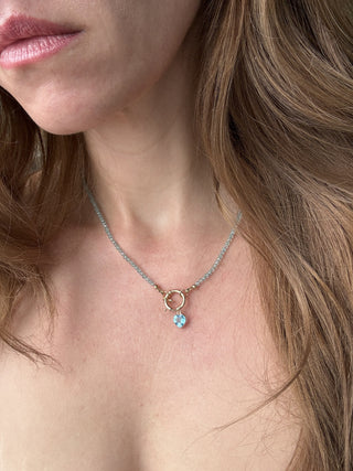 Blue topaz heart pendant styled on a chain necklace, shown worn at the neckline.