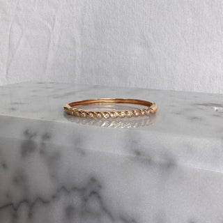 Angled view of a gold bangle with diamonds between curved gold details.