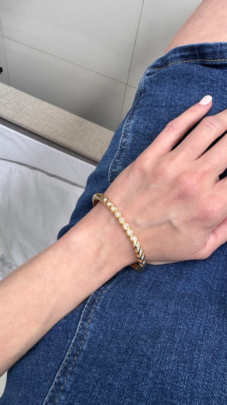 Gold diamond bangle worn on a wrist.
