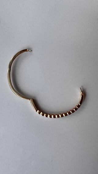 Gold diamond bangle opened to show its hinge and clasp.