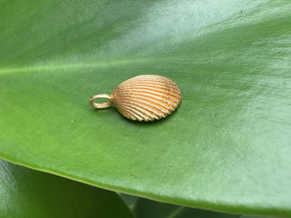 Angled view of a gold seashell pendant showing its depth.