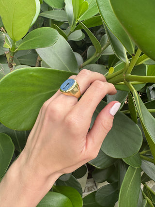 Blue chalcedony intaglio ring worn on a hand.