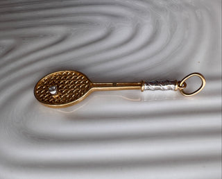 Gold tennis racket pendant with contrasting handle details and a small ball.
