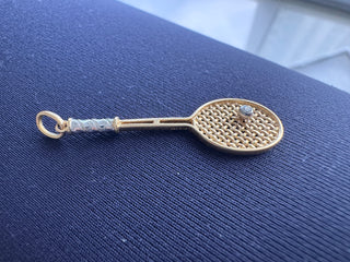 Gold tennis racket pendant with contrasting handle details and a small ball.
